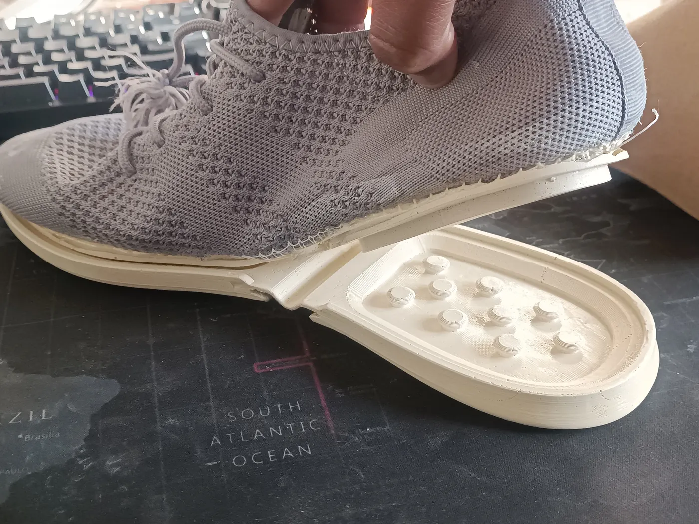 The grey prototype on a desk with its sole detached, the connector studs visible.