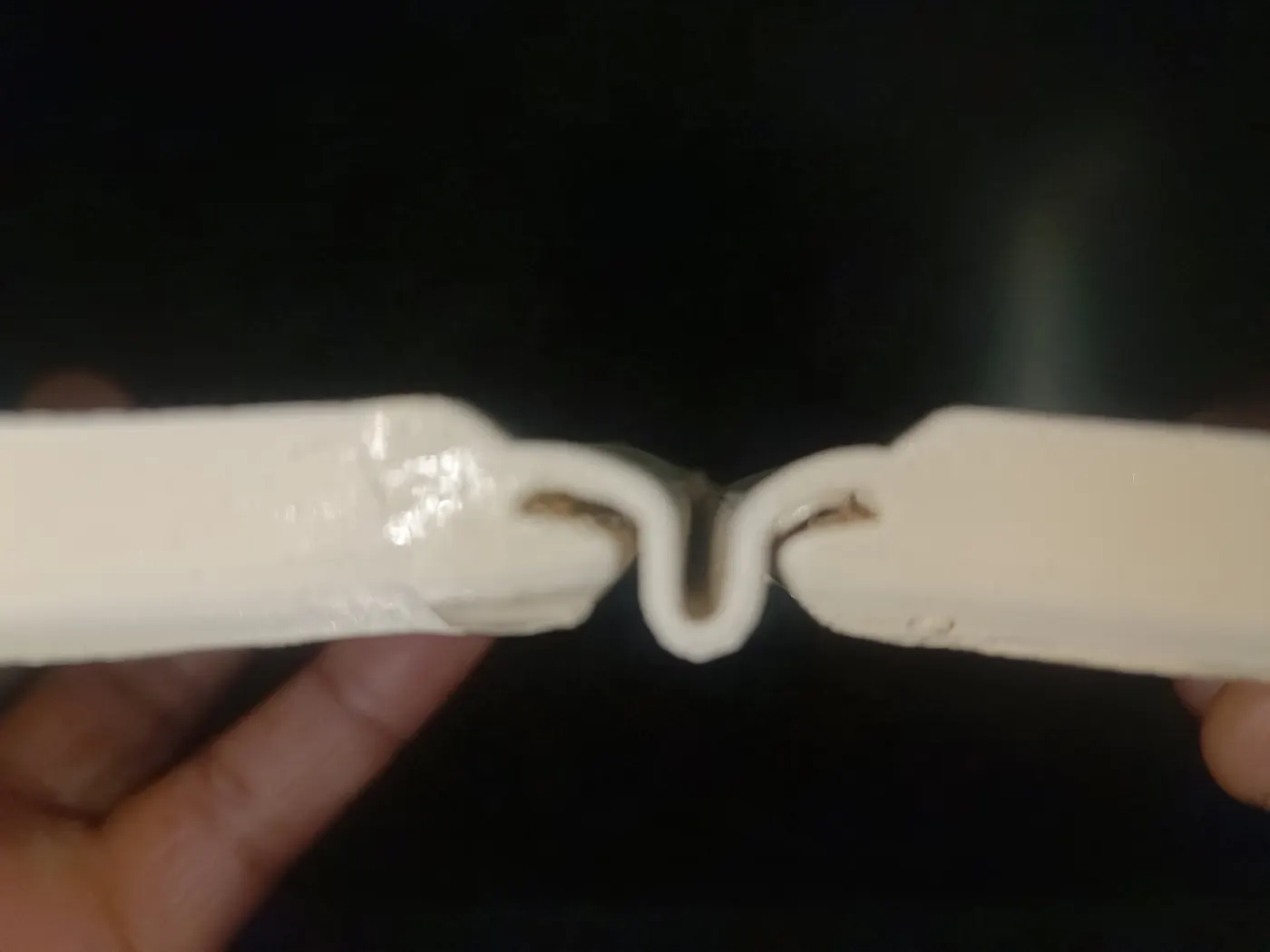 The 3D-printed connector, prototype 2, held between two fingers on the bench.
